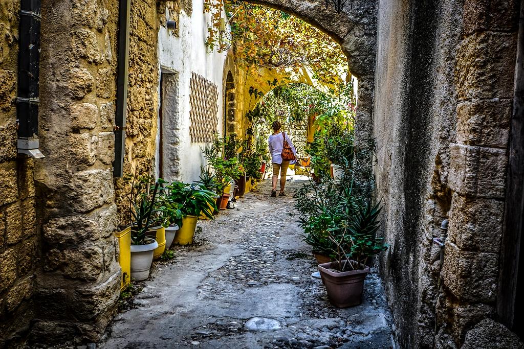 Solo traveler with backpack standing on mountain peak overlooking vast landscape